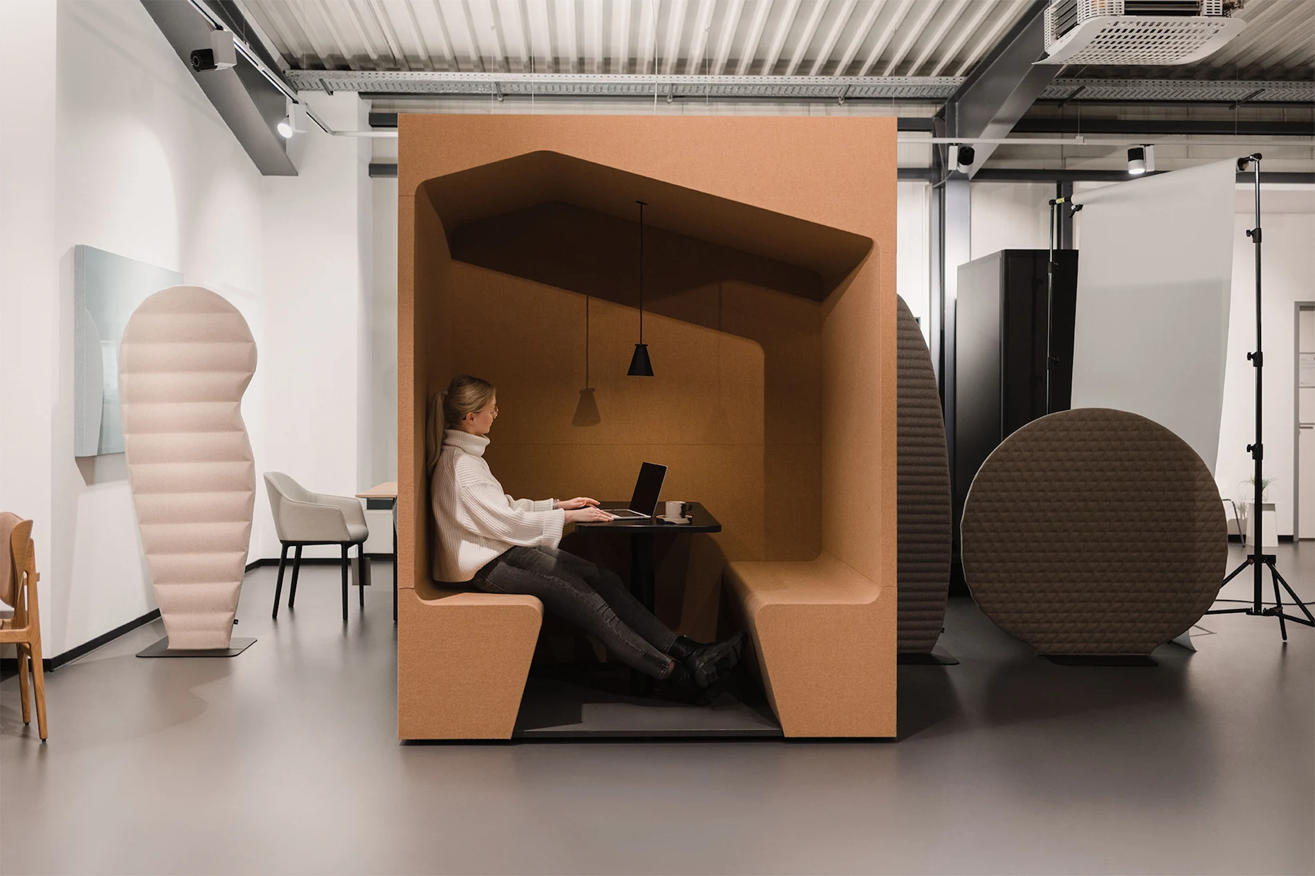 Minimalistisches Bürokonzept in Erdtönen mit eingegrenzter Sitzlounge und Arbeitsfläche.